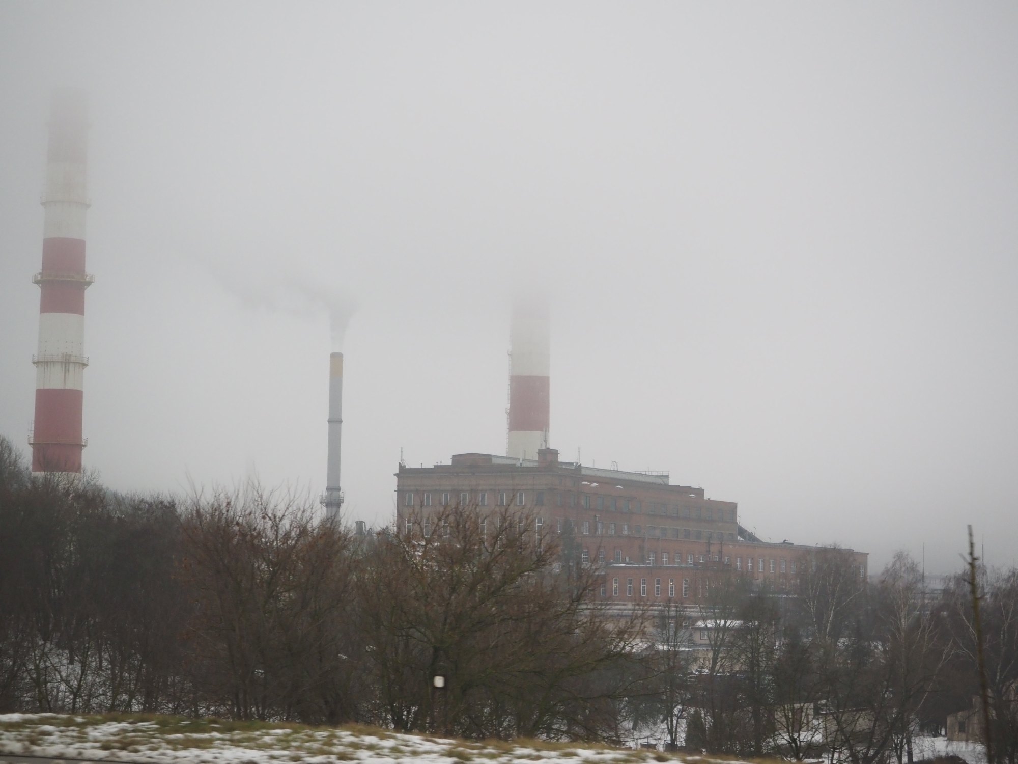 Fabrikschornsteine verschwinden im Nebel